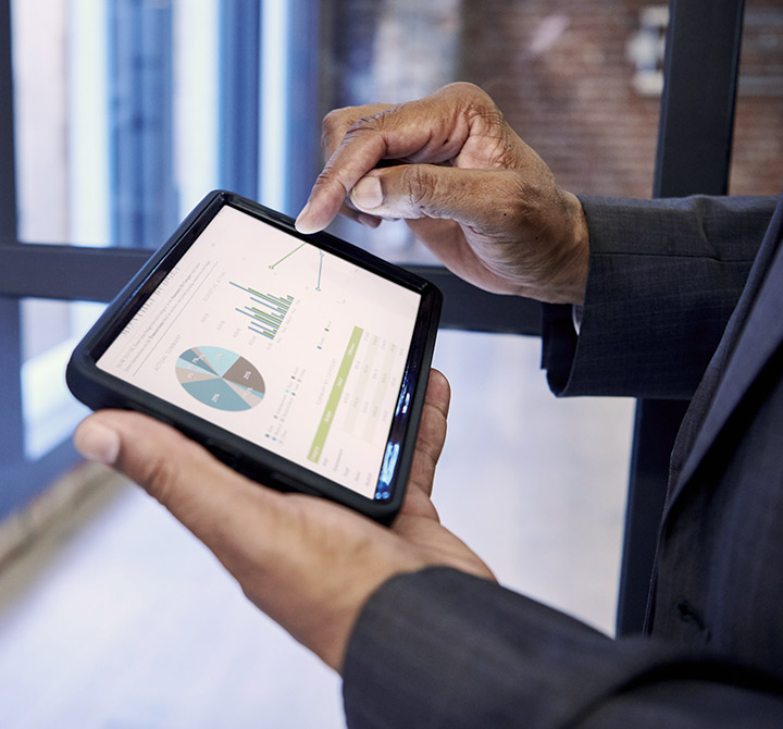 Tablet being held by office man with pie charts and graphs on screen. 