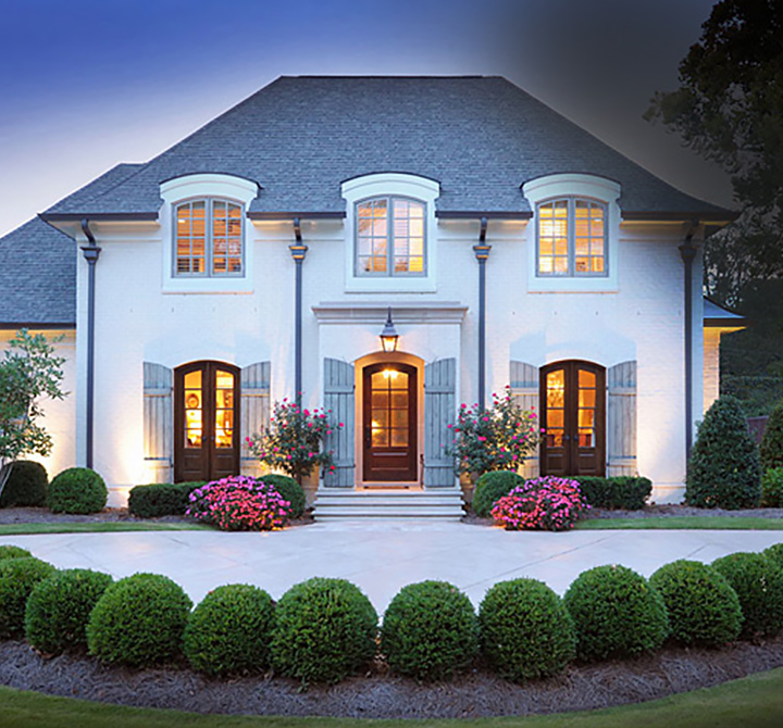 Front of a grand white 2 story house with excellent landscaping.