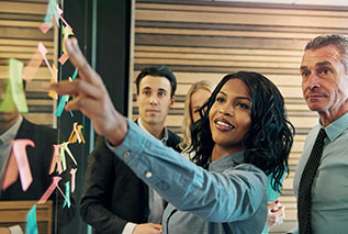 Workplace associates adding sticky notes to a glass wall